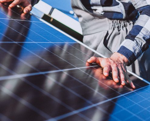 Fotografía de un hombre con la mano apoyada sobre un panel solar